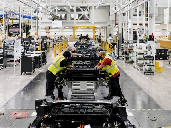 Employees assembling a car in a manufacturing plant.